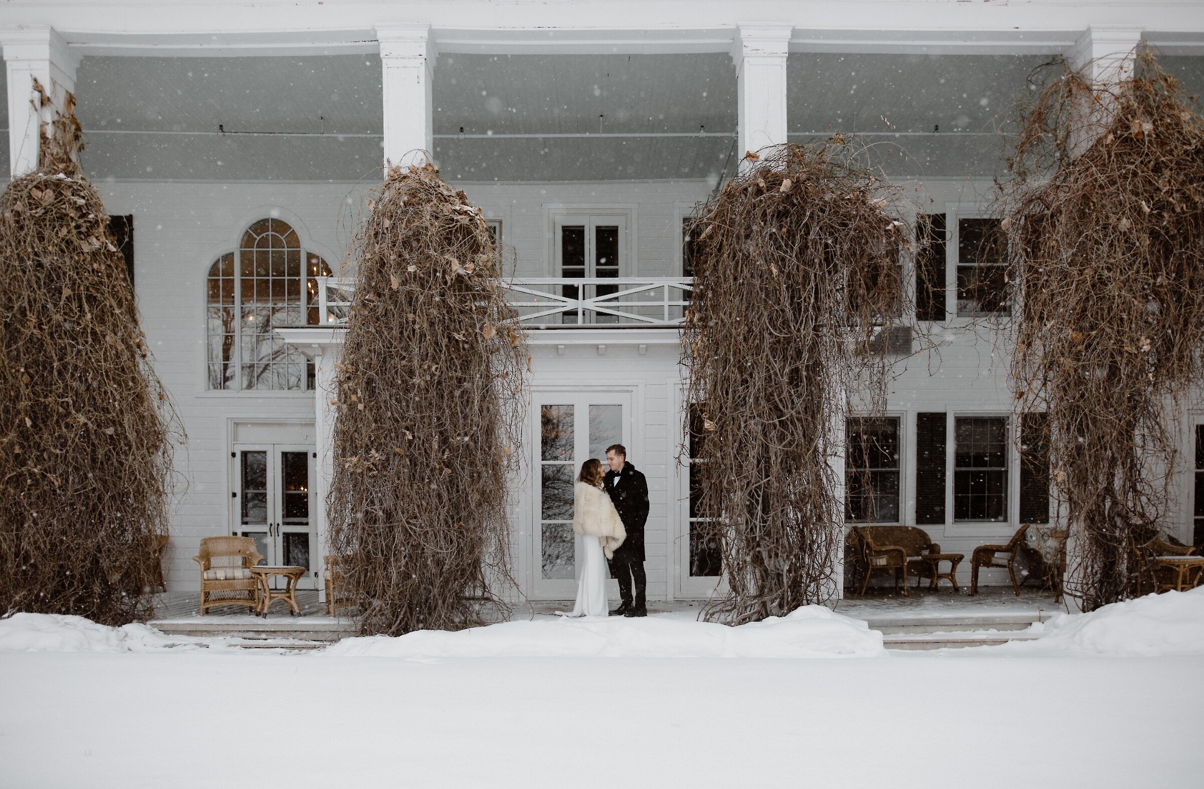 Deux invités sous les flocons devant la bâtisse